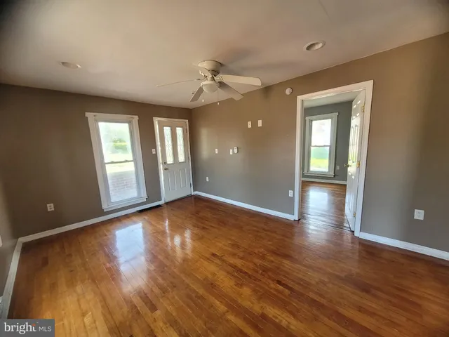 a view of an empty room with window and wooden floor
