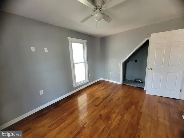 a view of empty room with wooden floor and fan