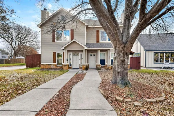 a front view of a house with a yard and large tree