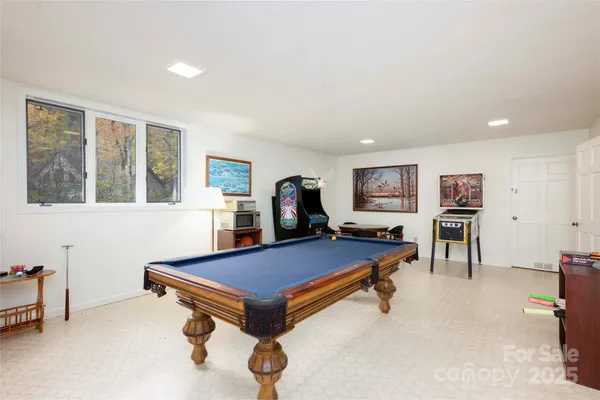 a living room with furniture pool table and windows