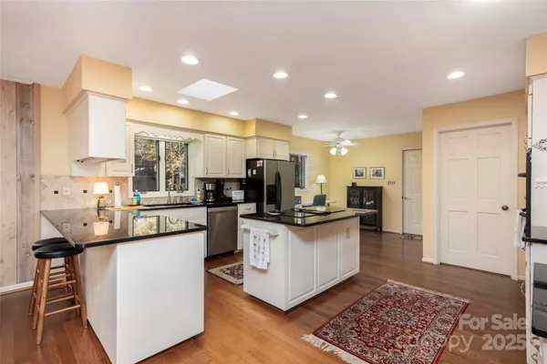 a kitchen with stainless steel appliances kitchen island granite countertop a sink and a refrigerator