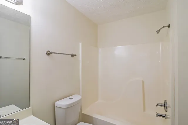 a white toilet sitting next to a bath tub