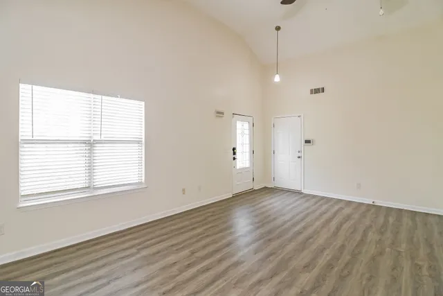 a view of an empty room with wooden floor and a window