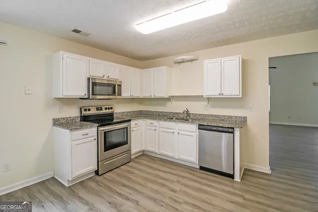 a kitchen with granite countertop white cabinets and appliances