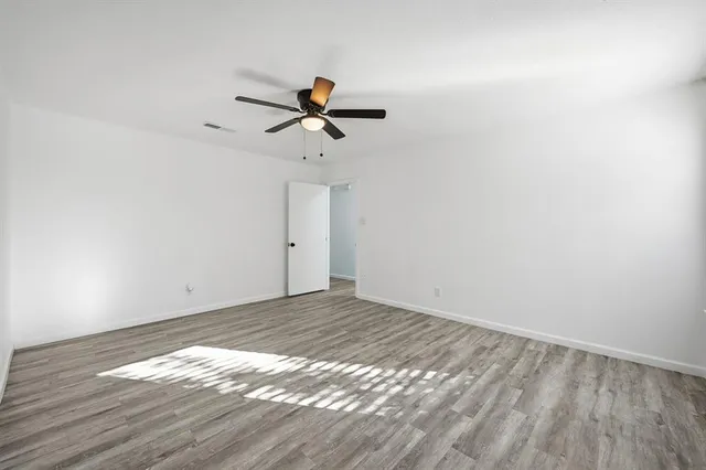 a view of a room with wooden floor and a ceiling fan