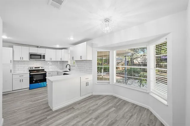 a kitchen with cabinets wooden floor and stainless steel appliances