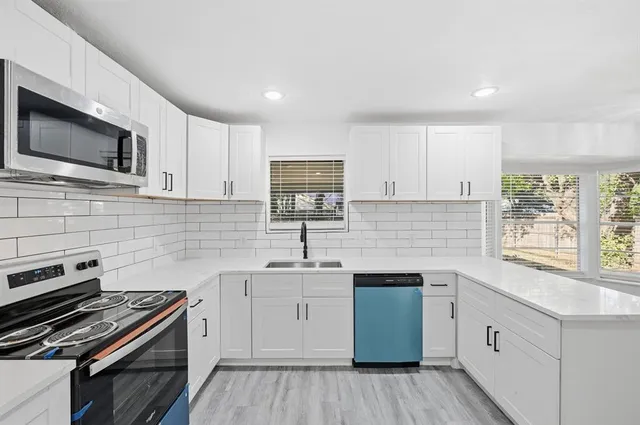 a kitchen with stainless steel appliances a sink stove and microwave