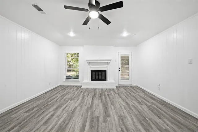 an empty room with ceiling fan and windows