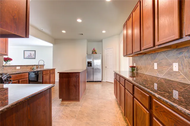 a kitchen with stainless steel appliances granite countertop a stove a sink and a refrigerator