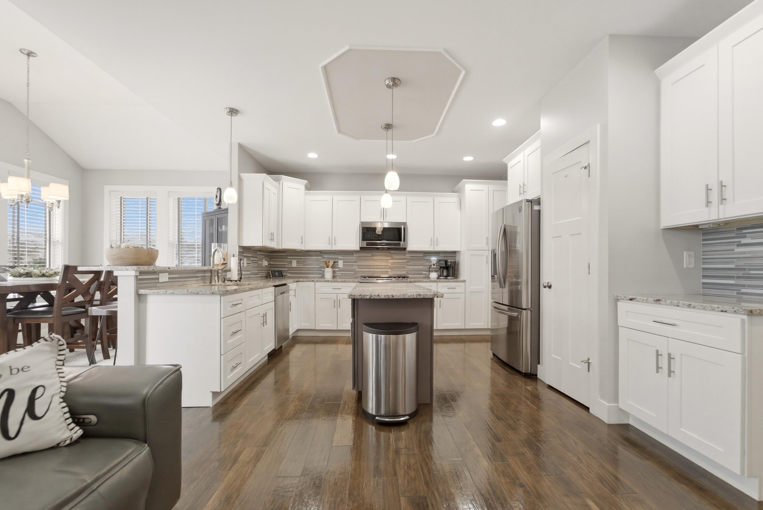 2102 Pradera Trail Chesterton, IN 46304 - Photo 25 of 50 a kitchen with stainless steel appliances kitchen island granite countertop a refrigerator a sink dishwasher a stove top oven a dining table and chairs with wooden floor