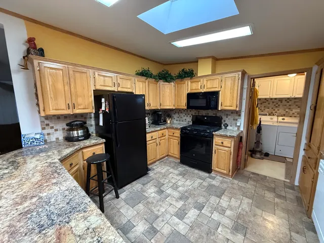 a kitchen with granite countertop a refrigerator a stove top oven a sink dishwasher and wooden cabinets