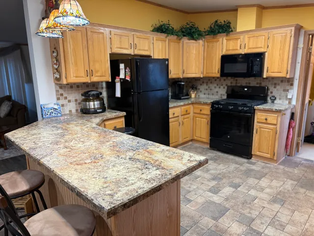 a kitchen with stainless steel appliances kitchen island granite countertop a refrigerator stove top oven and sink