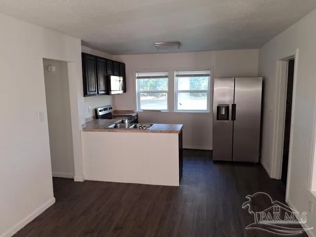 a view of a kitchen with wooden floor electronic appliances and windows