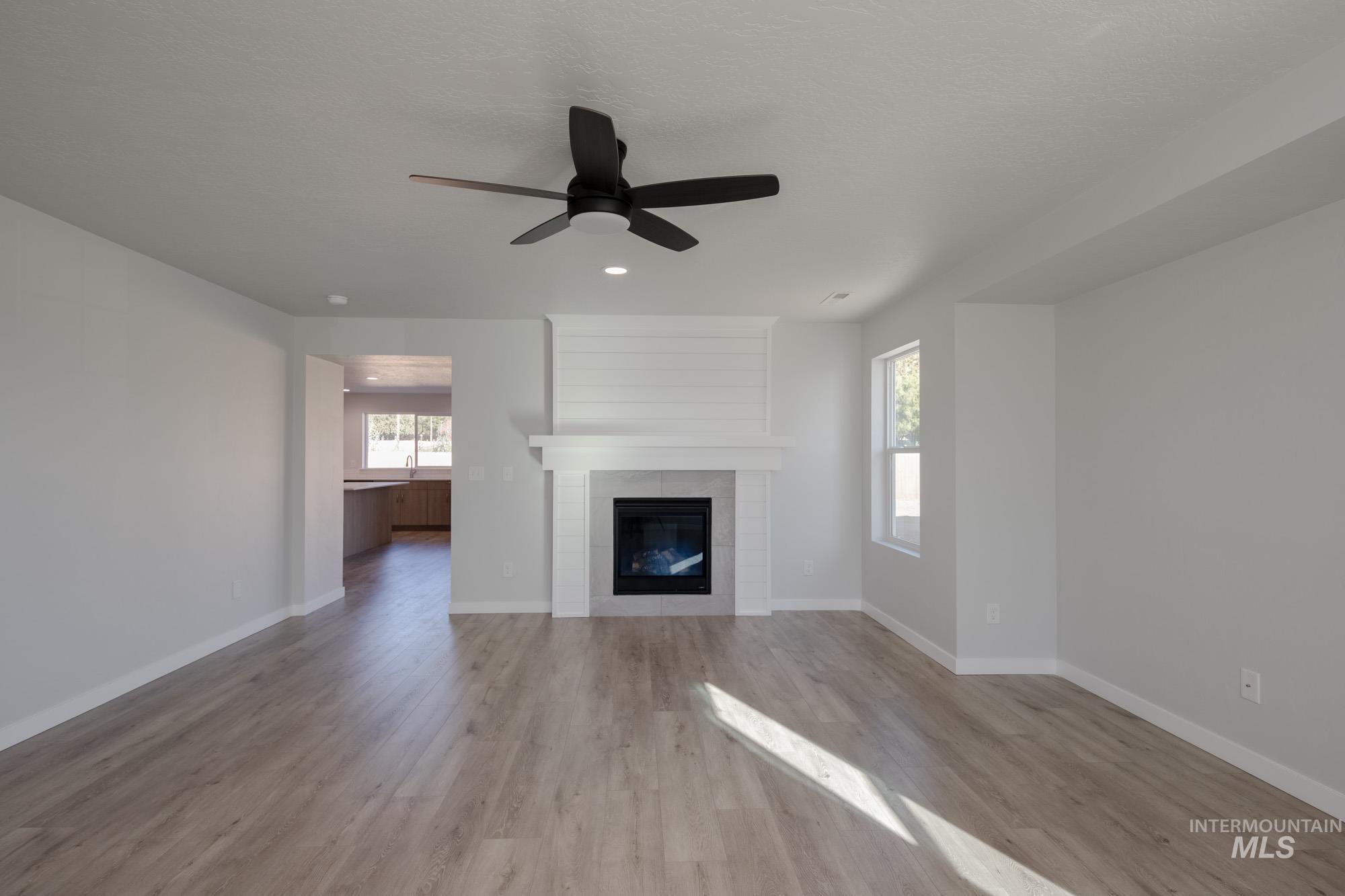1732 Webb Brk Street Middleton, ID 83644 - Photo 12 of 29 Unfurnished living room featuring a fireplace, light wood-style floors, a ceiling fan, and recessed lighting