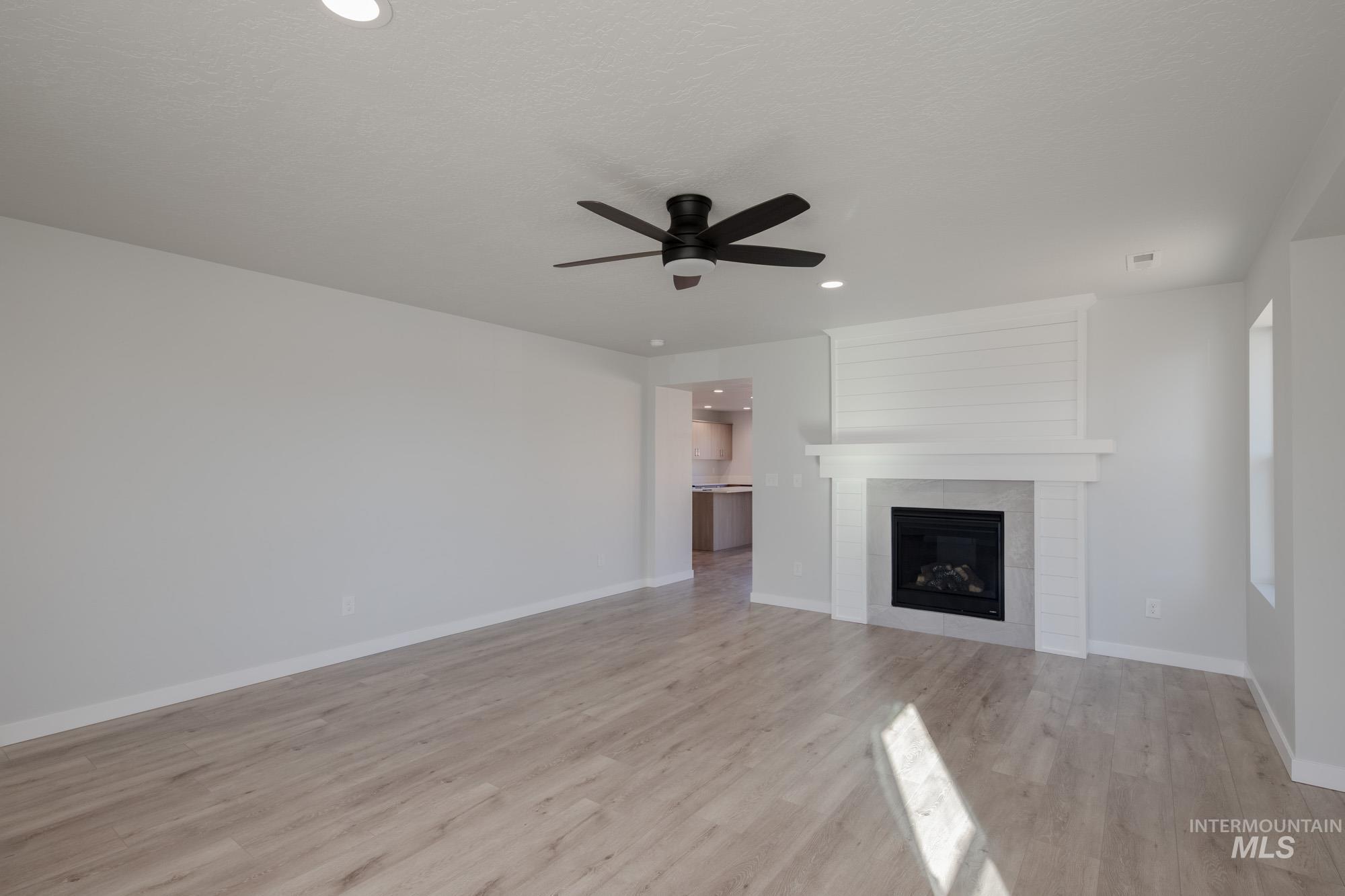 1732 Webb Brk Street Middleton, ID 83644 - Photo 13 of 29 Unfurnished living room featuring a fireplace, light wood finished floors, recessed lighting, and ceiling fan