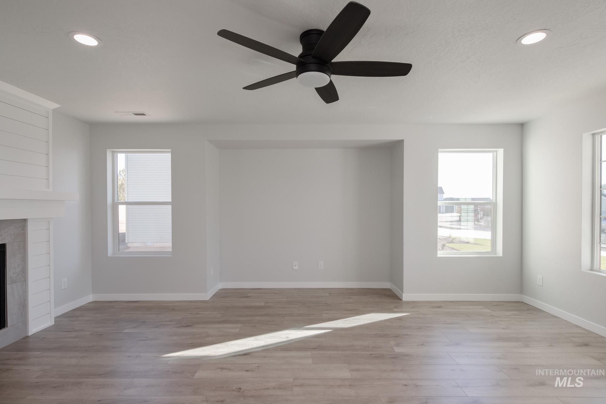 1732 Webb Brk Street Middleton, ID 83644 - Photo 14 of 29 Unfurnished living room featuring recessed lighting, plenty of natural light, light wood-type flooring, a large fireplace, and ceiling fan