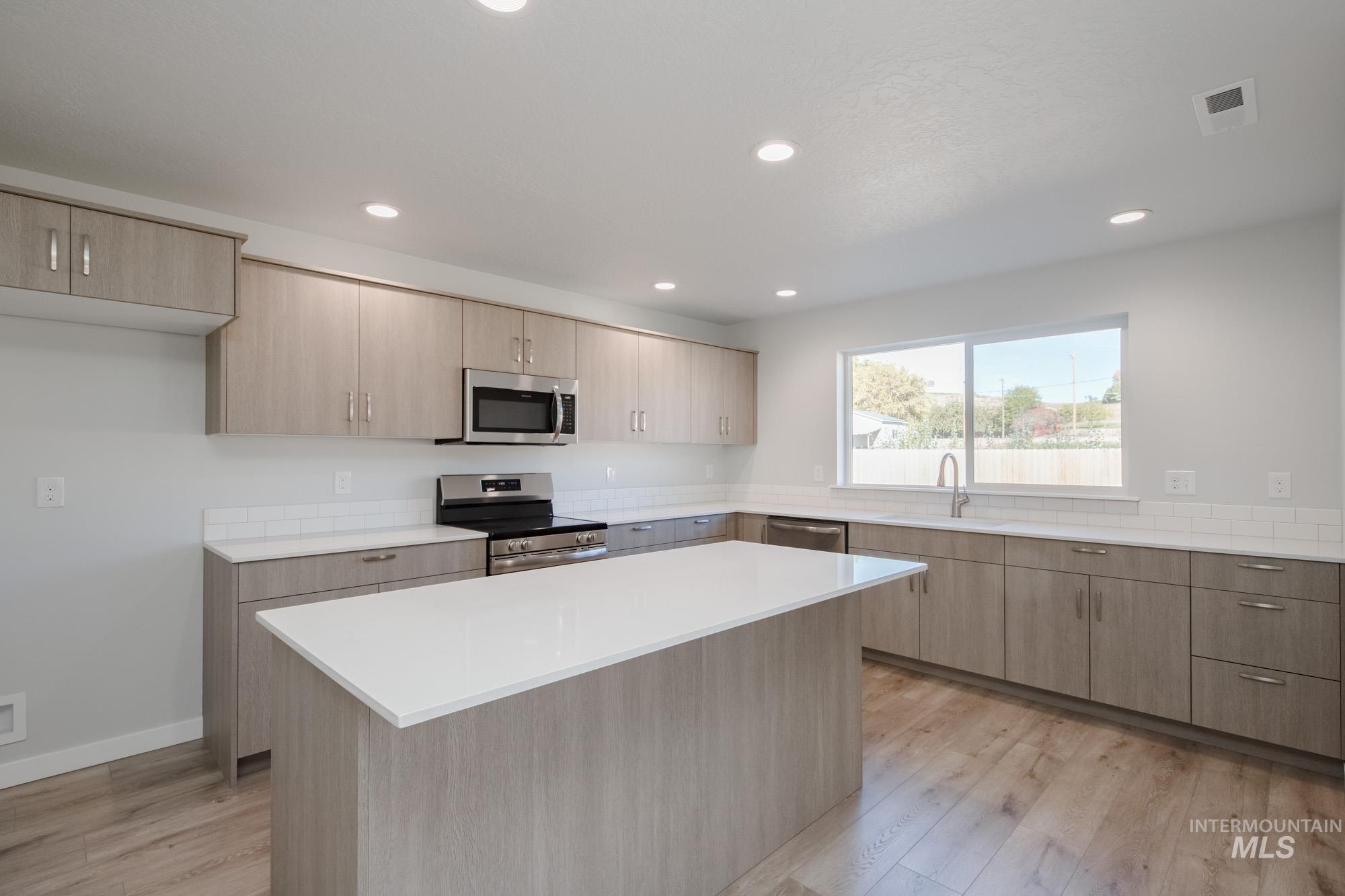 1732 Webb Brk Street Middleton, ID 83644 - Photo 4 of 29 Kitchen featuring light brown cabinetry, appliances with stainless steel finishes, modern cabinets, light wood-style flooring, and recessed lighting