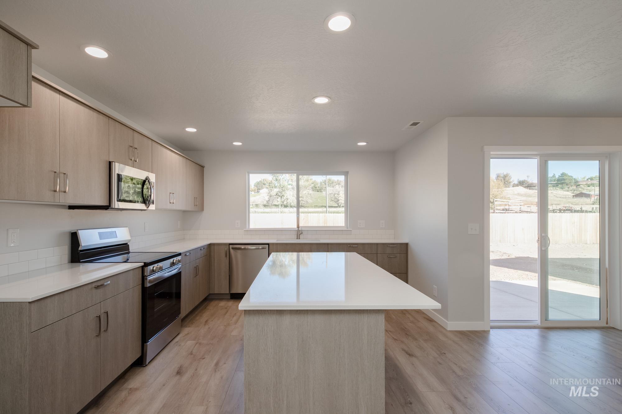 1732 Webb Brk Street Middleton, ID 83644 - Photo 8 of 29 Kitchen featuring appliances with stainless steel finishes, light brown cabinets, recessed lighting, light wood-style floors, and a center island