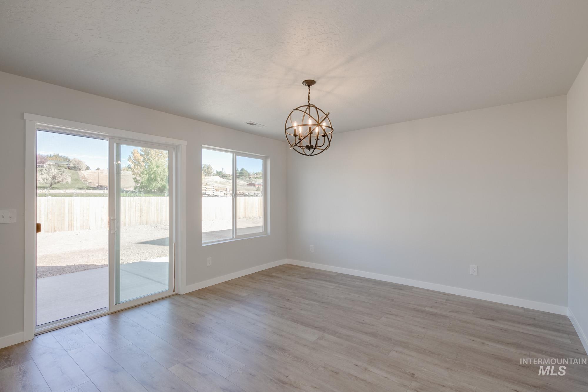 1732 Webb Brk Street Middleton, ID 83644 - Photo 9 of 29 Unfurnished room with light wood-style floors and a chandelier