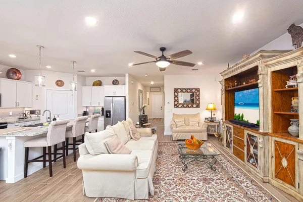 a living room with furniture a flat screen tv and kitchen view