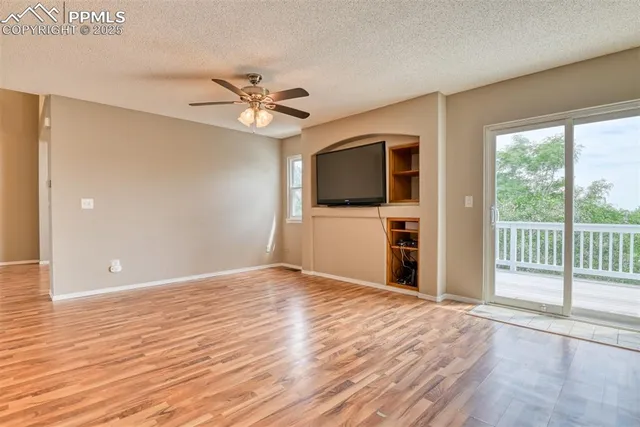 a view of a livingroom with a flat screen tv wooden floor and a ceiling fan