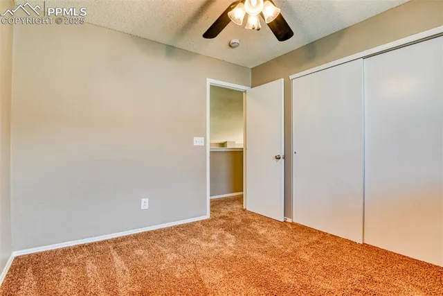 a view of an empty room and chandelier fan