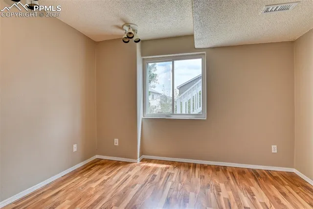 an empty room with wooden floor fan and windows