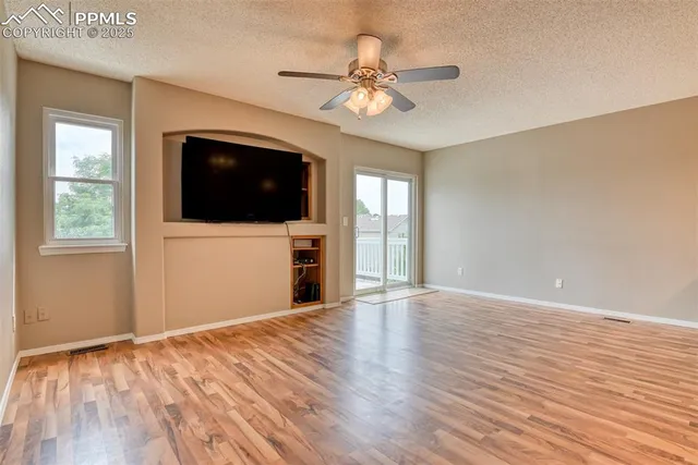 a view of a livingroom with a flat screen tv wooden floor and a ceiling fan