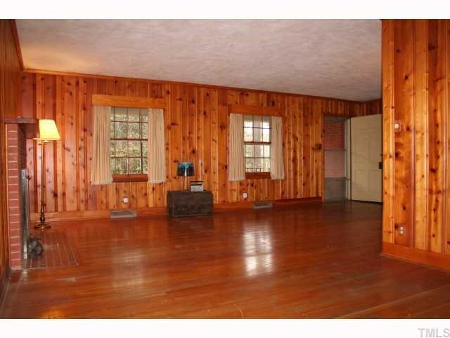 3115 Ridge Road Durham, NC 27705 - Photo 5 of 12 Large pine paneled Living Room has hardwood floors, real wood doors, a brick wood burning fireplace and access to the covered front porch.