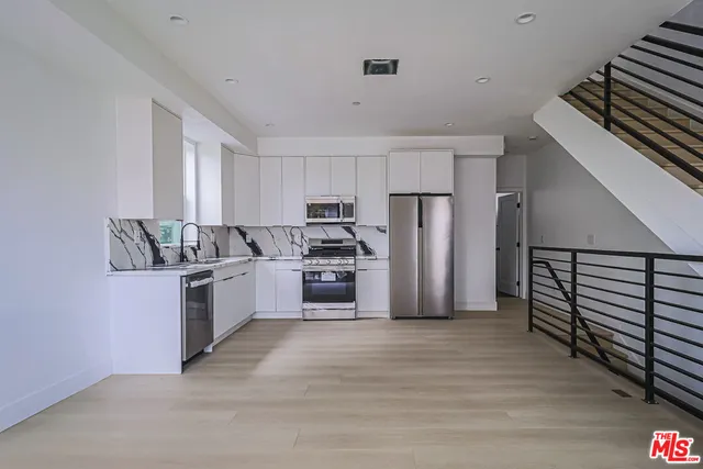 a kitchen with granite countertop a refrigerator oven a sink and dishwasher
