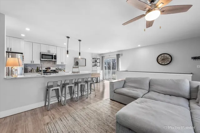 a living room with furniture kitchen view and a wooden floor