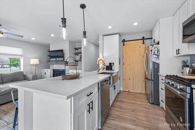 a kitchen with stainless steel appliances a stove a sink a refrigerator a center island and a stove