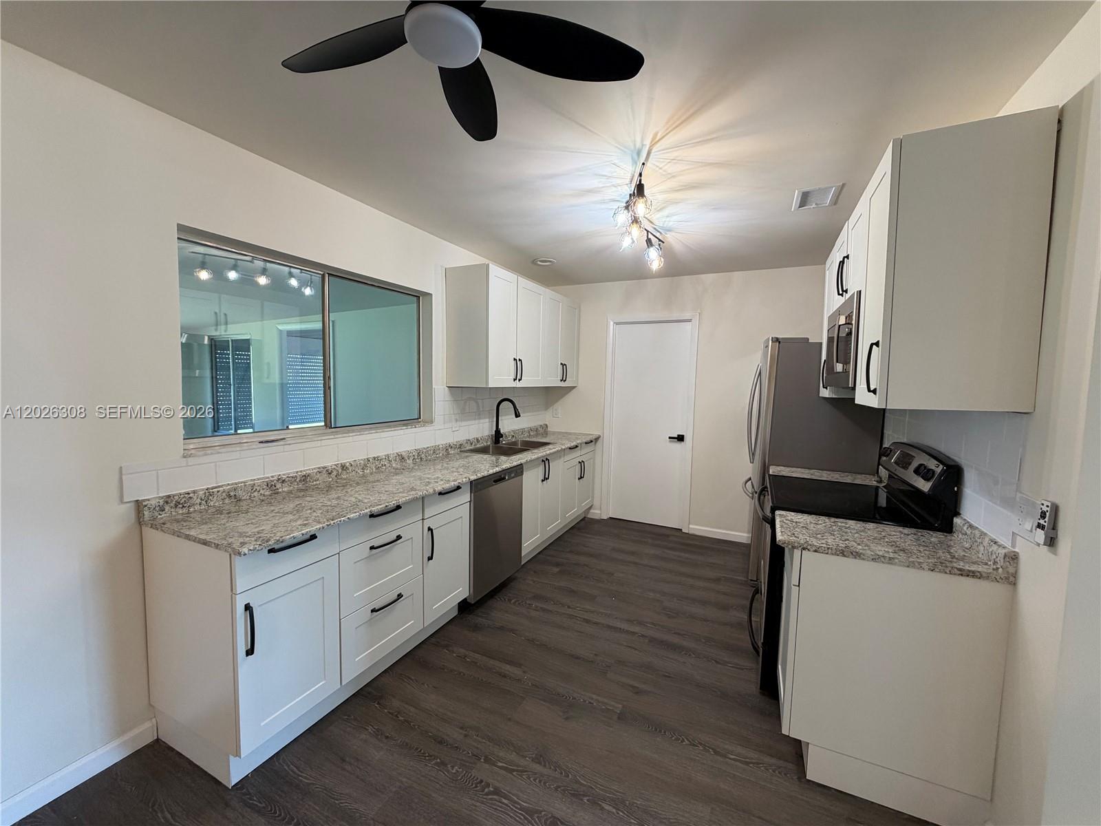 653 Atlas Avenue Northeast Palm Bay, FL 32905 - Photo 6 of 22 a kitchen with a stove window and cabinets