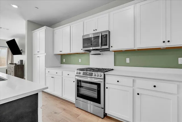 a kitchen with kitchen island a large counter top space a sink stainless steel appliances and cabinets