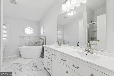 a spacious bathroom with a double vanity sink mirror and bathtub