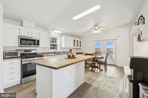 a kitchen with stainless steel appliances granite countertop a stove top oven a sink dishwasher a dining table and chairs with wooden floor