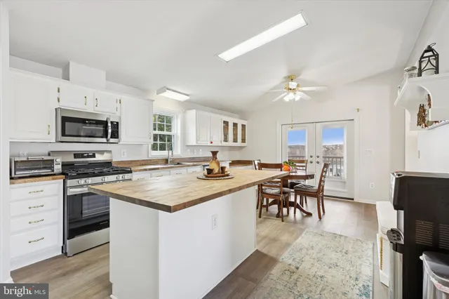 a kitchen with stainless steel appliances granite countertop a stove top oven a sink dishwasher a dining table and chairs with wooden floor