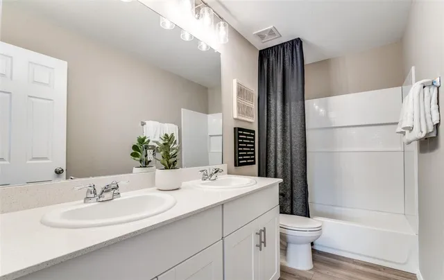 a bathroom with a double vanity sink toilet mirror and shower