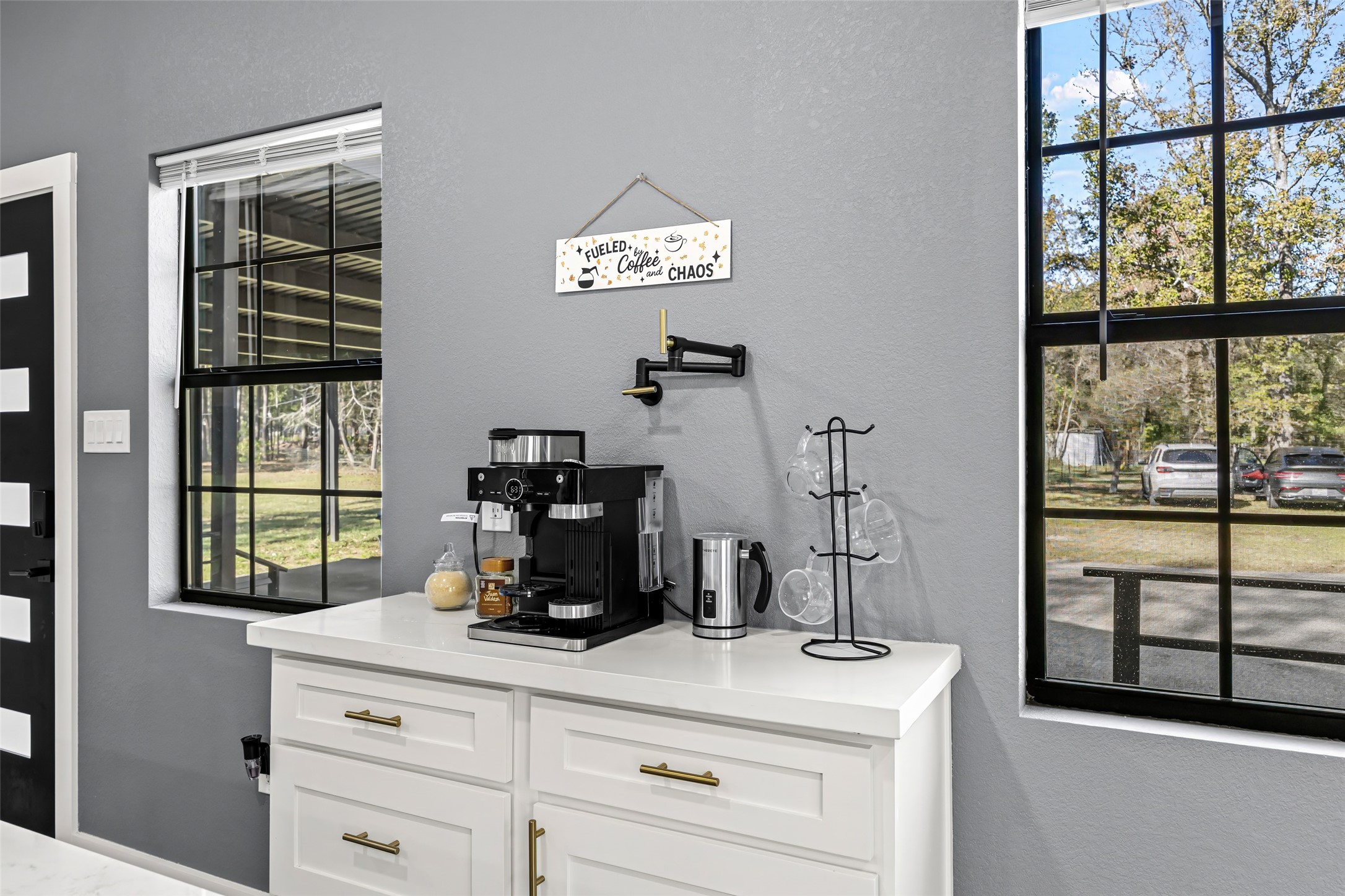 15080 Usher Lane Splendora, TX 77372 - Photo 15 of 44 This cozy kitchen nook features a modern coffee station with a sleek machine and cup holder on a white countertop. It's framed by large windows offering a view of the yard, creating a bright and inviting space.