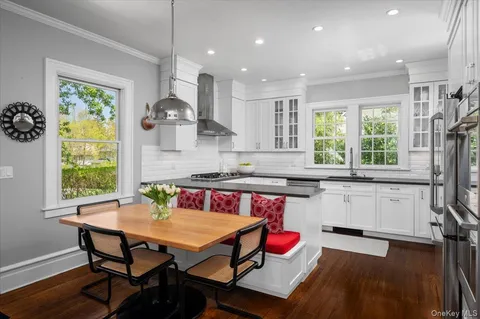 a kitchen with stainless steel appliances granite countertop a stove a sink dishwasher a dining table and chairs with wooden floor