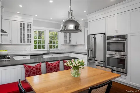 a kitchen with stainless steel appliances a dining table chairs and refrigerator