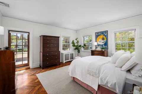 a bedroom with a bed a dresser and a large window