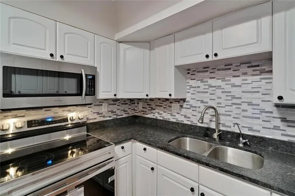 a kitchen with sink a microwave a stove and cabinets