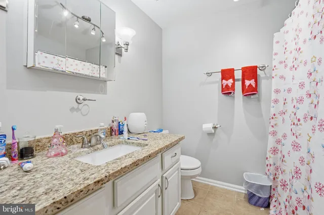 a bathroom with a granite countertop sink mirror vanity and toilet