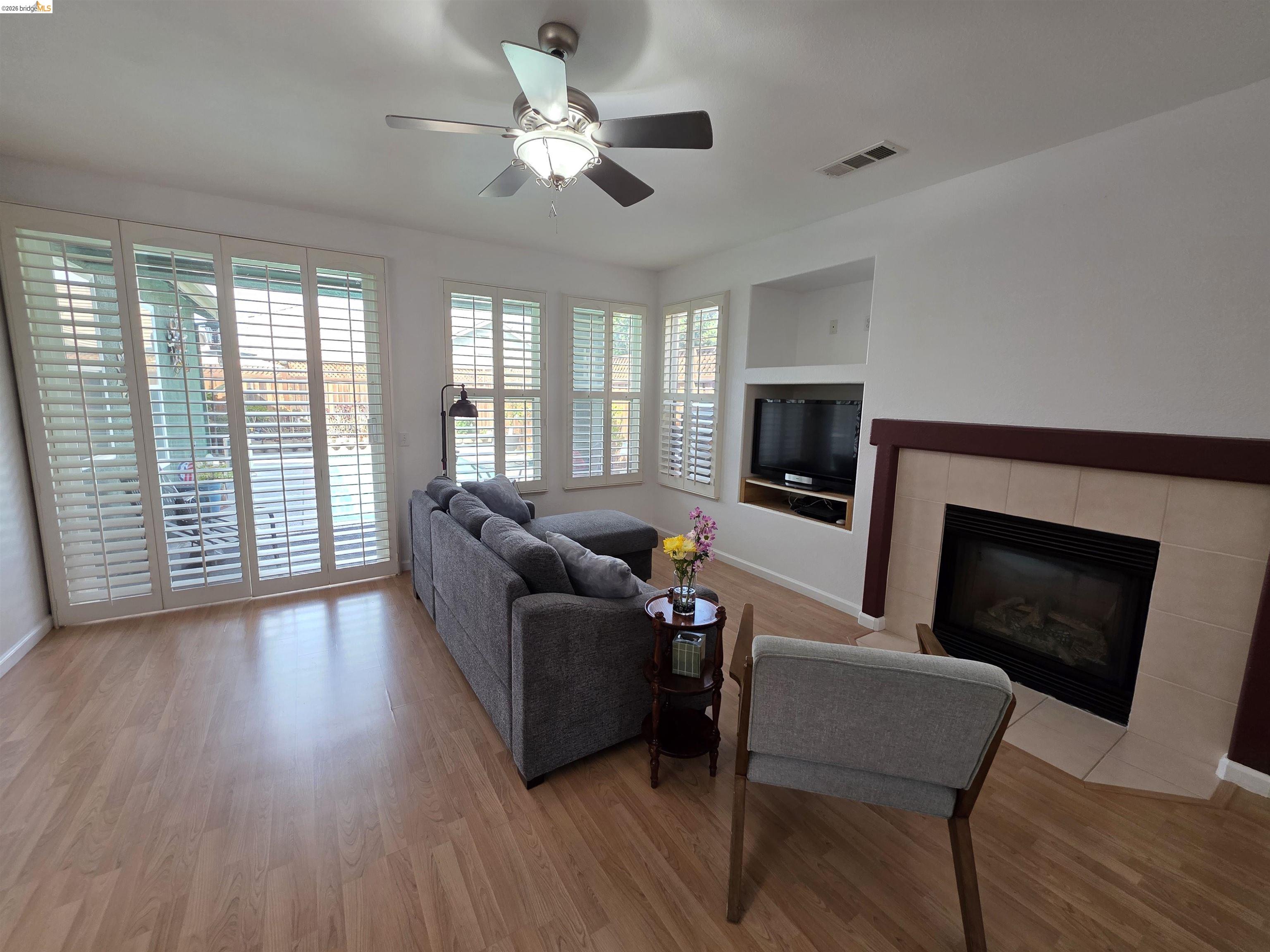 2607 Glow Road Riverbank, CA 95367 - Photo 12 of 42 Wood-finish flooring, built-in entertainment niche, recessed lighting, ceiling fan, and a fireplace with a tile surround