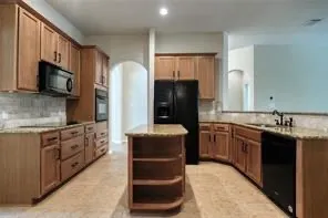 a kitchen with stainless steel appliances granite countertop a refrigerator a stove a sink and a microwave