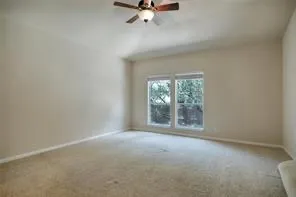 an empty room with chandelier fan and windows