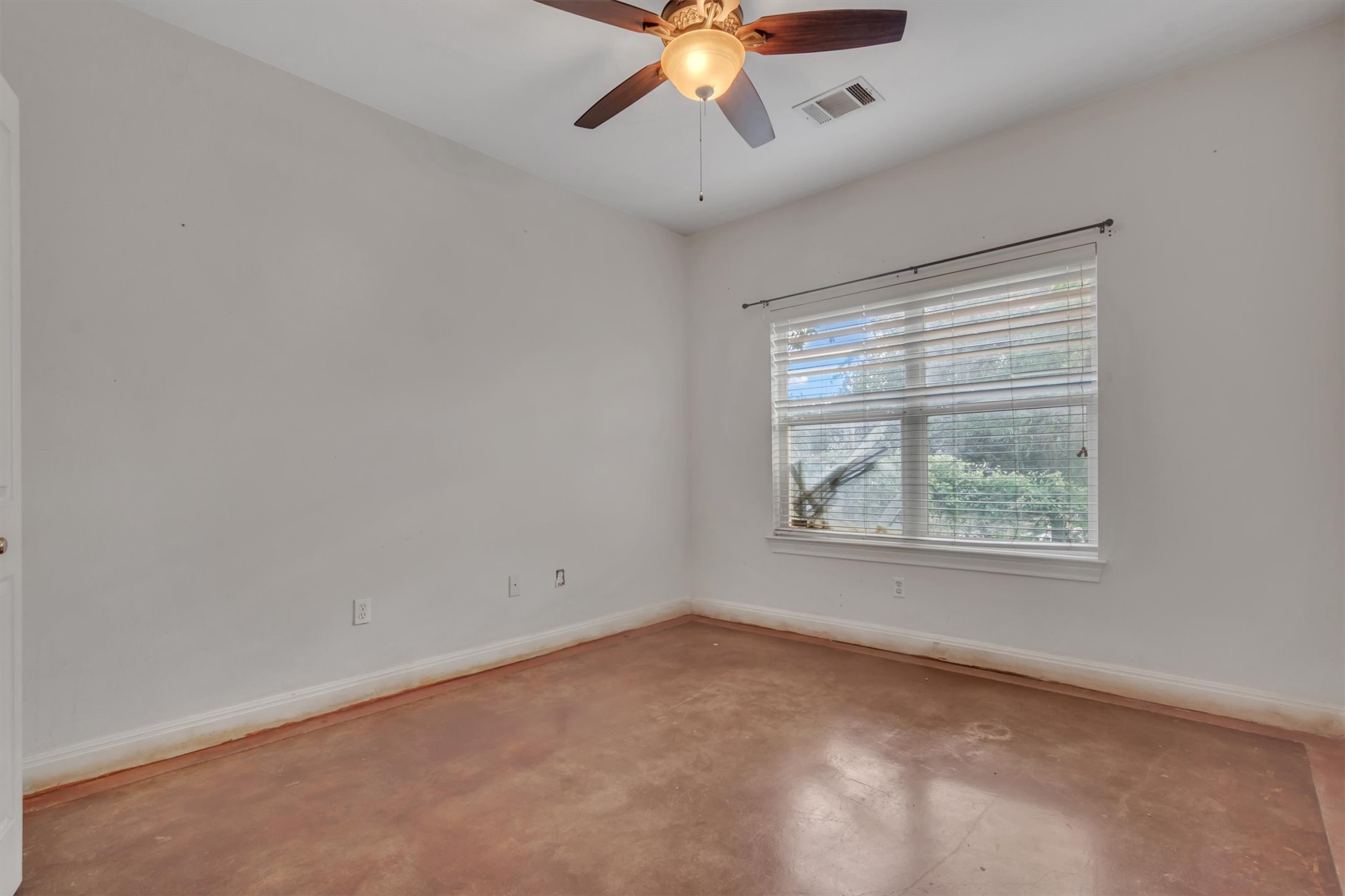 1120 Meadow Ridge Drive Austin, TX 78737 - Photo 25 of 40 A well-lit bedroom with durable concrete flooring and a ceiling fan for comfort.