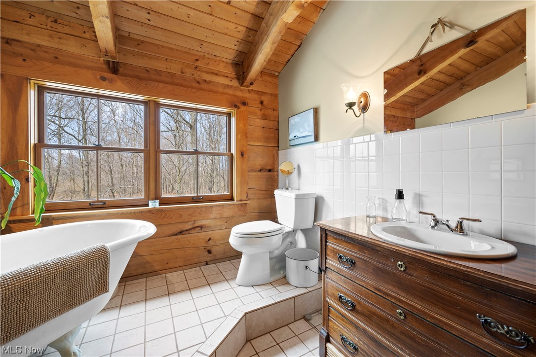 9485 Stone Road Litchfield, OH 44253 - Photo 37 of 50 Bathroom featuring lofted ceiling with beams, tasteful backsplash, tile floors, toilet, and a healthy amount of sunlight