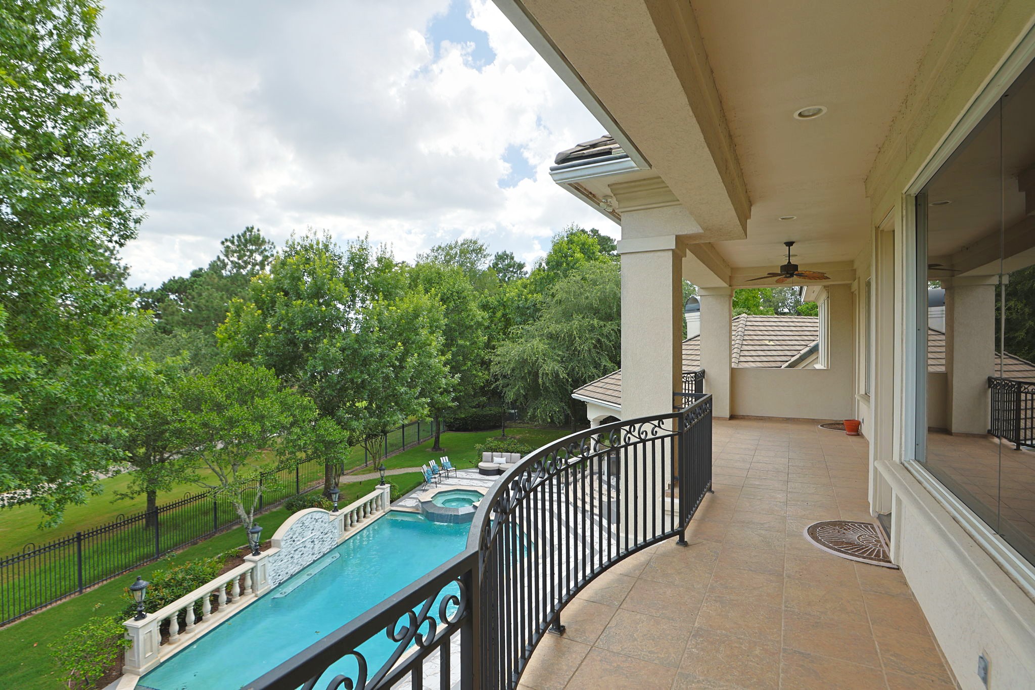 39 Maymont Way Spring, TX 77382 - Photo 27 of 50 This photo shows a spacious balcony overlooking a beautiful backyard with a pool and spa, surrounded by lush greenery, providing a serene and private outdoor retreat.